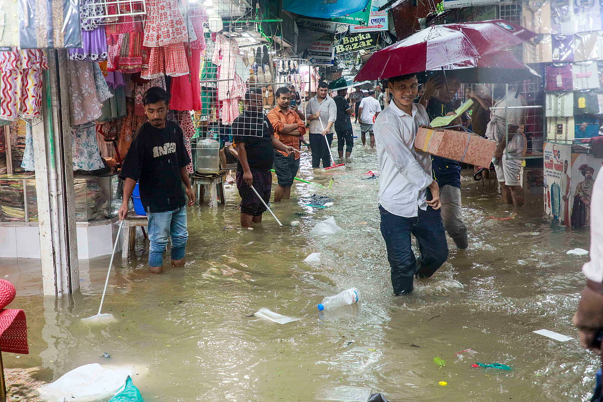 Shop employees using buckets and brooms to remove rainwater from inside their shops.