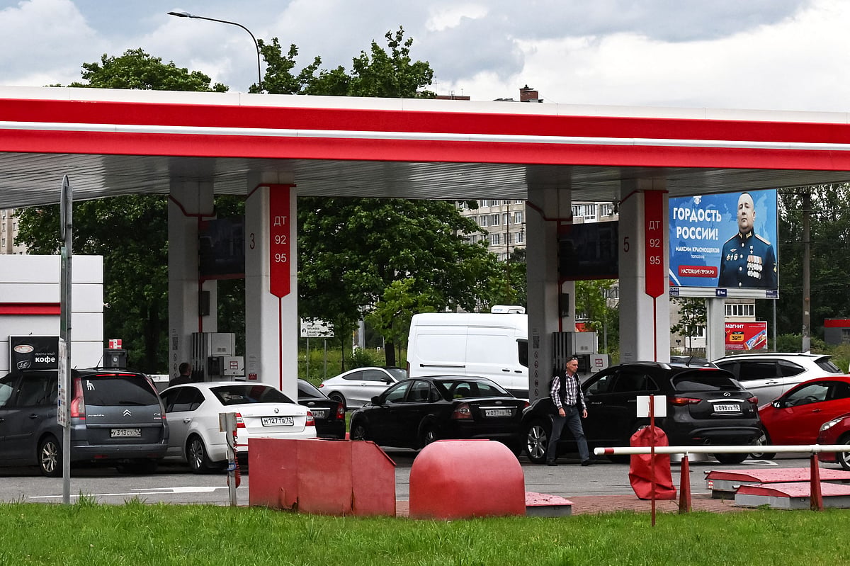 People queue to refuel their cars at a Lukoil gas station, with a billboard honouring a participant in Russia's military action in Ukraine and reading "The proud of Russia" seen behind it, in Saint Petersburg on 7 July, 2026.