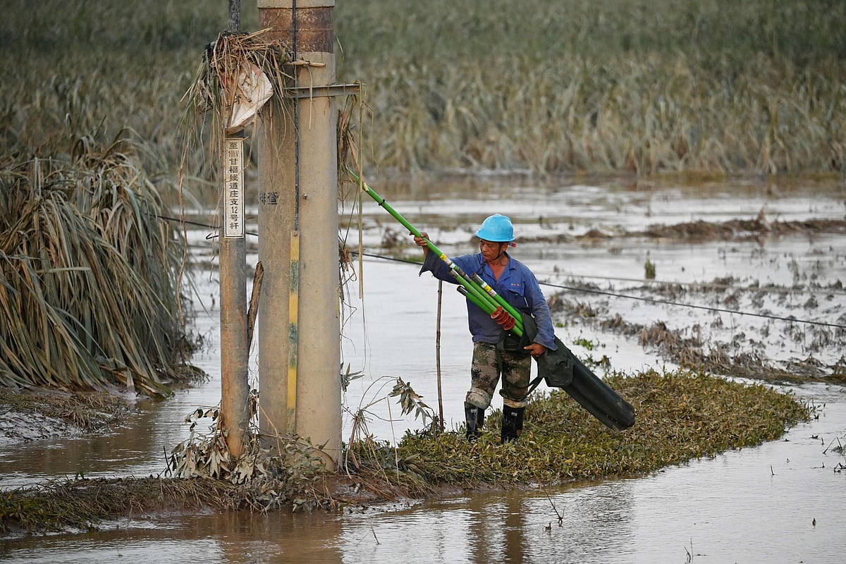 An electrical worker prepares to repair electrical lines that were downed by floodwaters from a collapsed reservoir near Gantang, in China's southwest Guangxi region on 9 July 2026. The death toll from devastating floods in southern China's Guangxi region rose to 39 on 9 July, with nine people still missing, state media reported, as residents went about cleaning up.