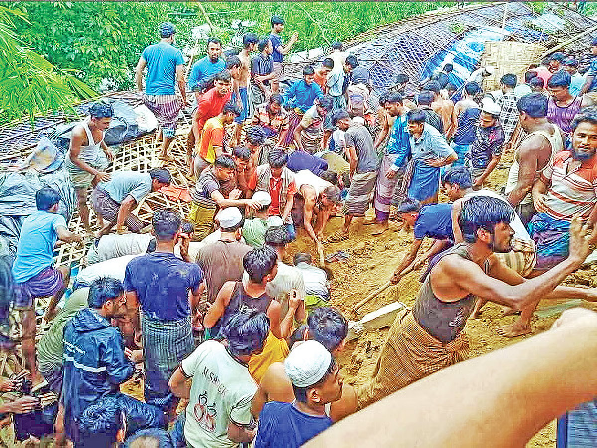 Local residents take part in rescue efforts after three Rohingya children, who were students at a madrasah, were buried beneath earth when a hillside retaining wall collapsed at a refugee camp in Ukhia, Cox's Bazar. The photograph was taken in the afternoon on 8 July 2026