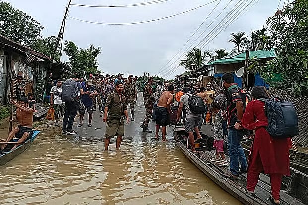 Tourists cross a flooded section of the road in the Baghaihat area of Sajek, Rangamati, with assistance from the Bangladesh Army and local residents.