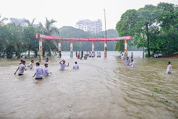 A group of students play in the rain at the flooded Rabindra Sarobar plaza.