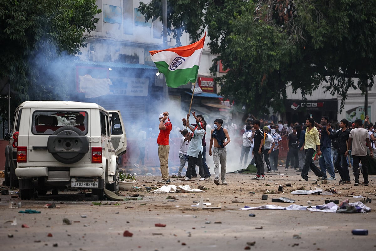 Masked protesters hold an Indian flag near plumes of tear gas as supporters of India's Cockroach Janta Party demonstrate on the opening day of the Indian parliament's monsoon session, demanding the resignation of Education Minister Dharmendra Pradhan over exam paper leaks, in New Delhi, India, 20 July, 2026.