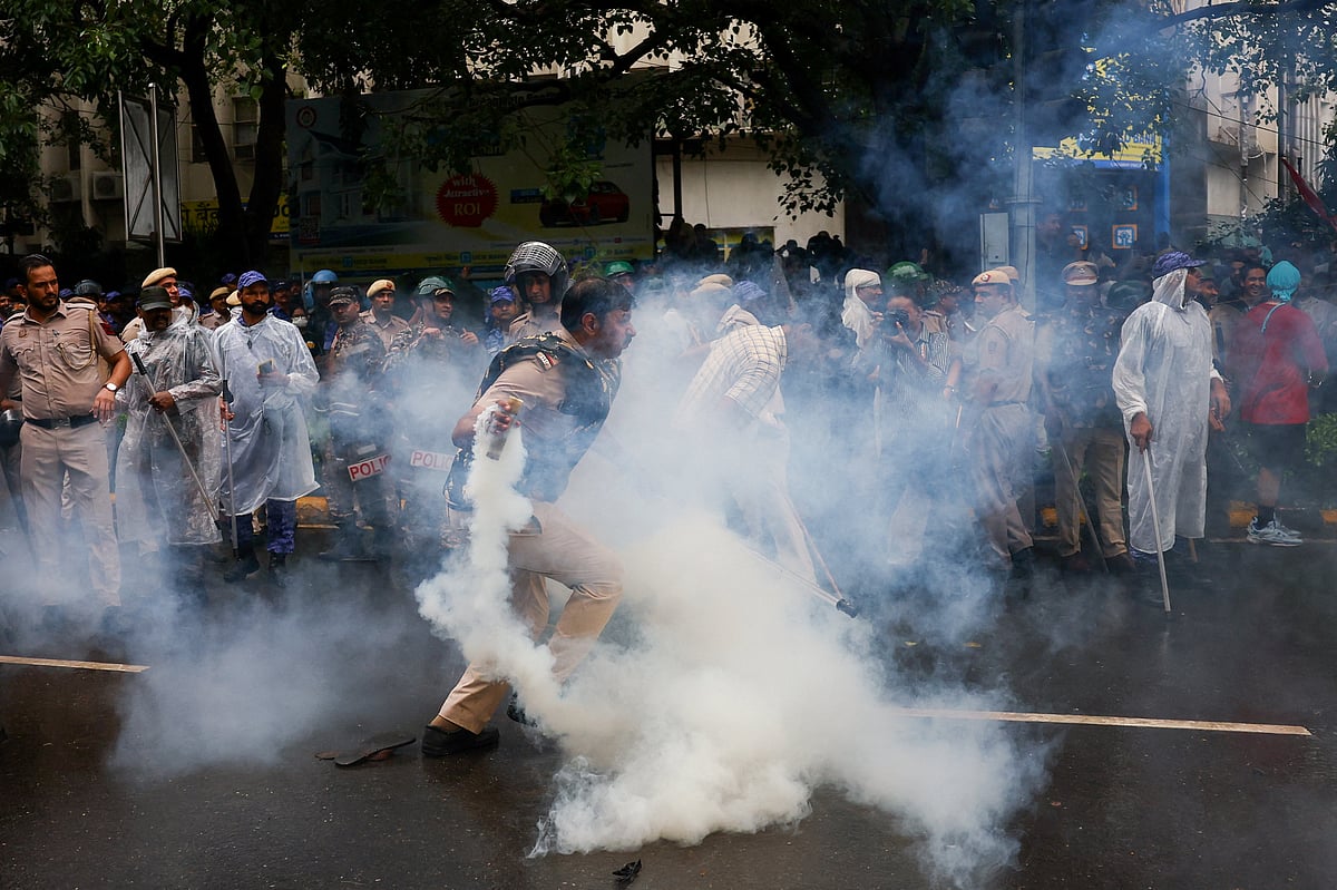 A police officer picks up a tear gas shell after it was thrown back by the protesters, as supporters of India's Cockroach Janta Party demonstrate on the opening day of the Indian parliament's monsoon session, demanding the resignation of Education Minister Dharmendra Pradhan over exam paper leaks, in New Delhi, India, July 20, 2026.