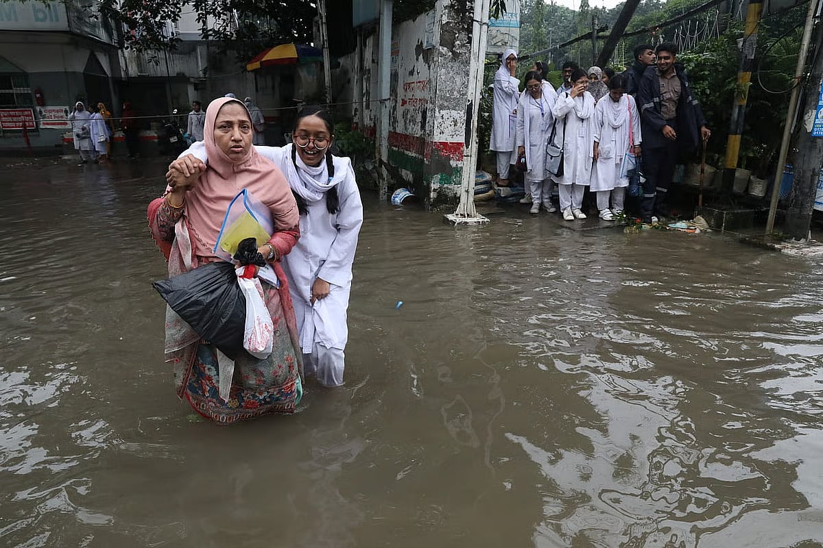 A HSC candidate makes her way through floodwater after completing her examination, supported on the shoulders of her guardian, at the T&T College examination centre in the Fakirapul area of Dhaka. The photograph was taken around midday on 6 July 2026.