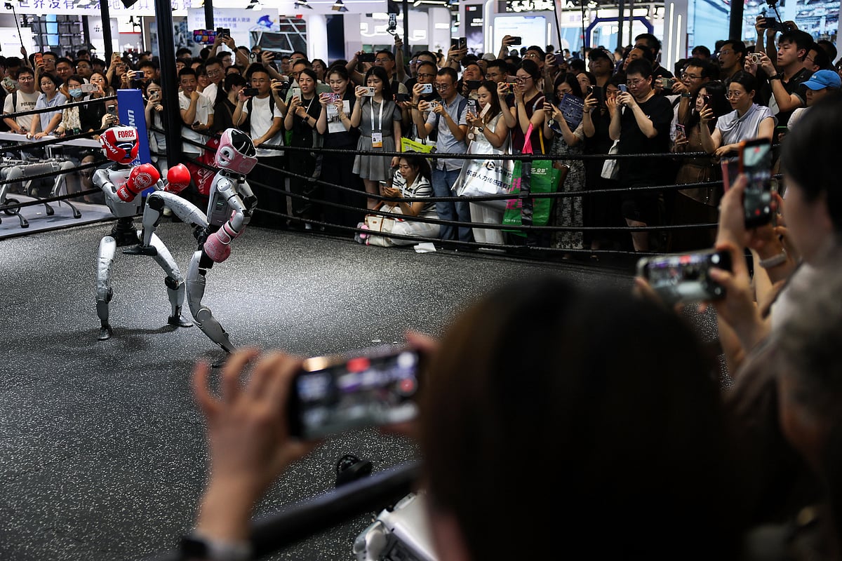 Visitors watch two humanoid robots kickbox at the Unitree booth during the World Artificial Intelligence Conference (WAIC) in Shanghai, China, on 18 July 2026