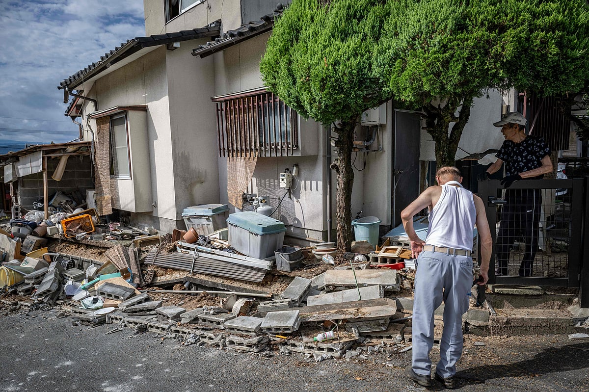 Akira Motoda (R) talks with a neighbour beside a collapsed concrete block wall of his house damaged by the 7.1-magnitude earthquake in Uki city, Kumamoto Prefecture on July 29, 2026. Thirteen people died after a major quake in Japan, Prime Minister Sanae Takaichi said on July 29, as rescue workers desperately tried to reach others feared trapped in a badly damaged shopping mall and a factory.