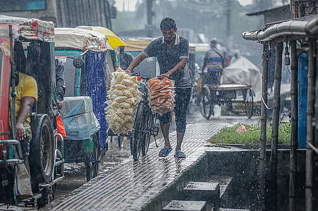 A small trader braves the rain on his bicycle to sell popcorn and other snacks. Rayermahal, Khulna, 30 July.