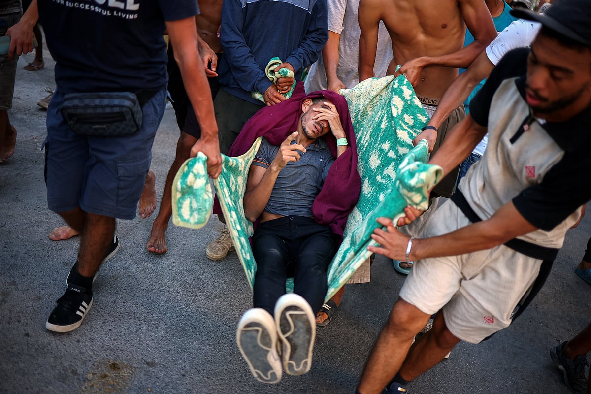 Migrants carry a fellow migrant, who they say was injured when the Spanish police and military tried to contain the migrants to an area of a beach, in Ceuta, Spain, 2 August, 2026.
