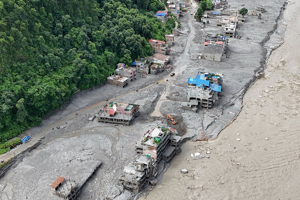 TOPSHOT - An aerial view shows a torrent of muddy water surging past houses and through the Trishuli River in the aftermath of flash floods at Trishuli Center in Nepal's Nuwakot district on September 1, 2026. Devastating floods on the China-Nepal border have killed at least 987 people in Nepal, the disaster authority said on September 1, taking overall deaths to more than 1,000. (Photo by Arun SANKAR / AFP)
