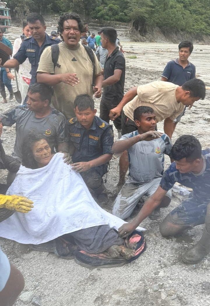 Rescuers gather near a woman after she was rescued from a house, following deadly flash floods and a mudslide, at a location given as Nuwakot, Nepal in this still image from video released 5 September 2026.