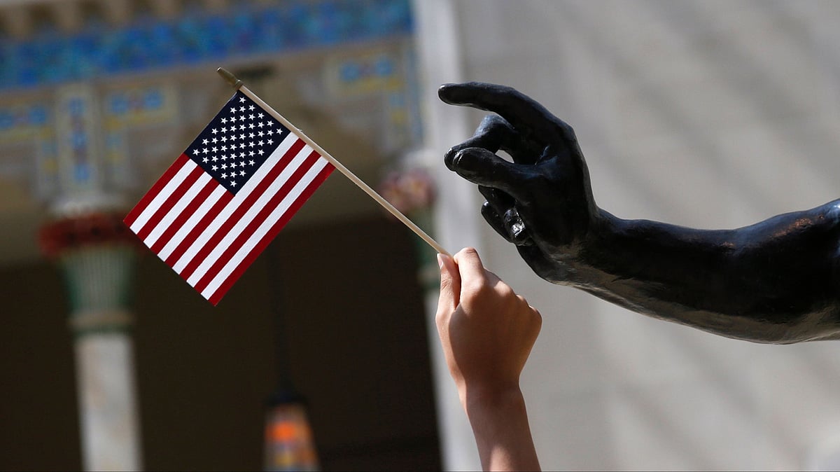 A girl holds a US flag next to a sculpture after a naturalization ceremony at The Metropolitan Museum of Art in New York 22 July 2014.