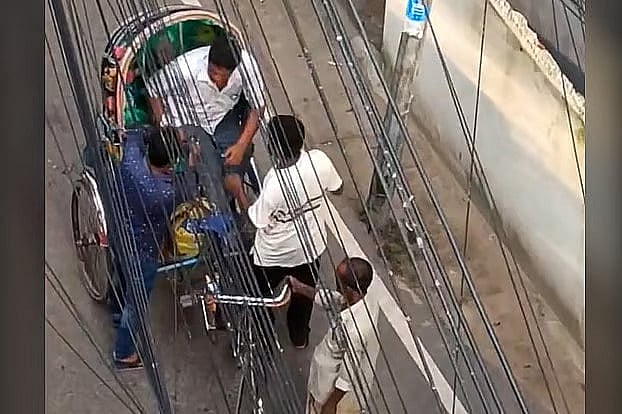 A rickshaw passenger is being mugged after being stopped. Police identified by the person white T-shirt on the right as Saddam Hossain.
