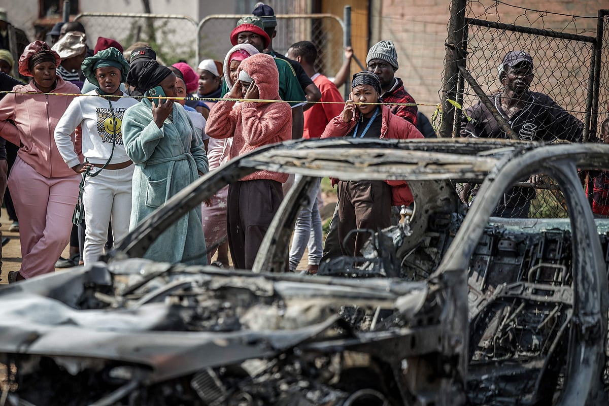 Residents stand behind police tape near the scene where gunmen armed with assault rifles stormed a bar in Johannesburg on September 27, 2026. Gunmen killed at least 27 people in two mass shootings in South Africa's two main cities, police said on September 27, 2026, in the latest violence to hit the crime-weary country.