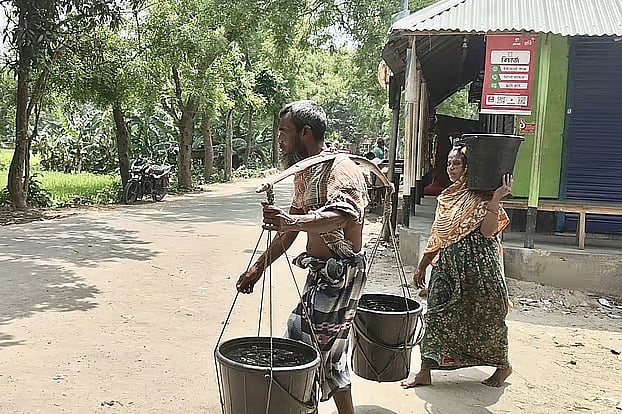 Family members collect water in buckets from a deep tube well located far from their home for drinking and household use. Kondail village, Tanore Upazila, Rajshahi, 14 April.