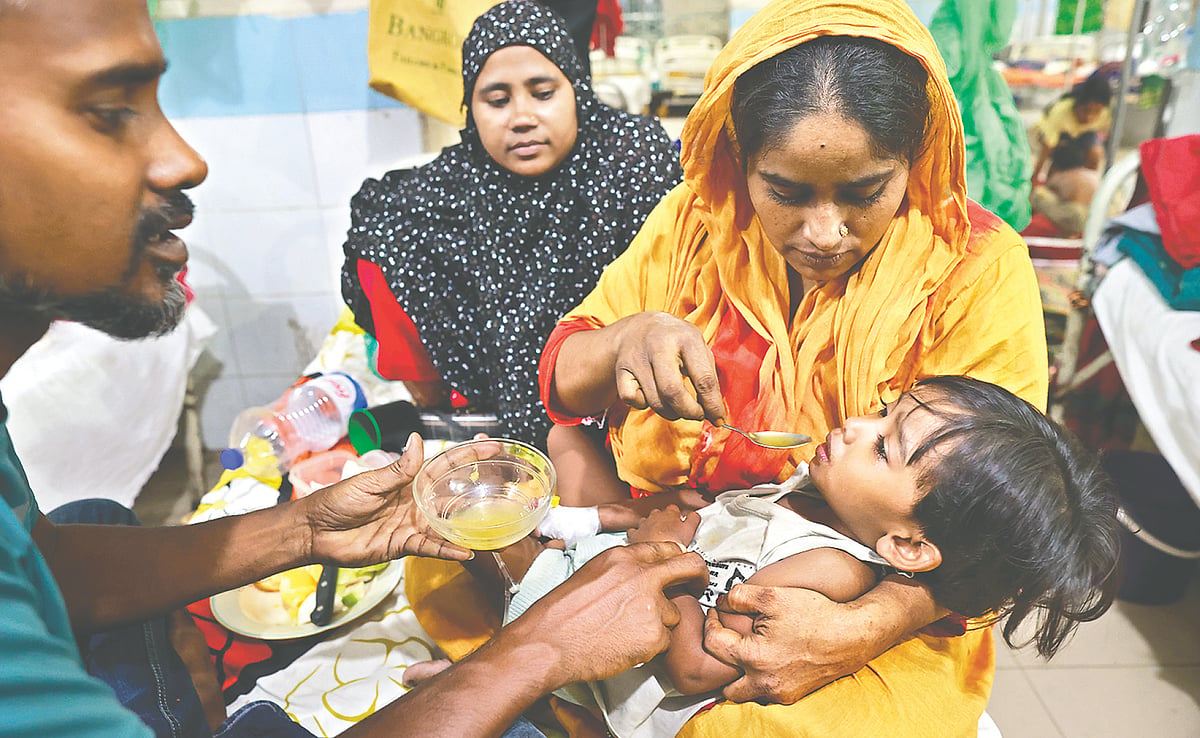 Three-year-old Fatiha, a dengue patient, receives care from a family member at Mugda Medical College Hospital.