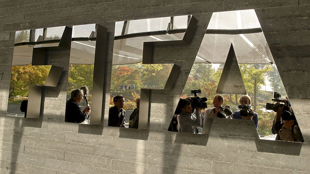 Journalists are reflected in a logo at the FIFA headquarters after a meeting of the executive committee in Zurich