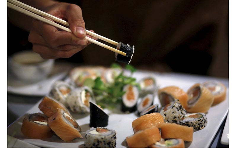 A woman uses chopsticks to eat sushi at a restaurant in La Serena, Chile, June 18, 2015. International Sushi Day has been marked on June 18 annually since 2009.