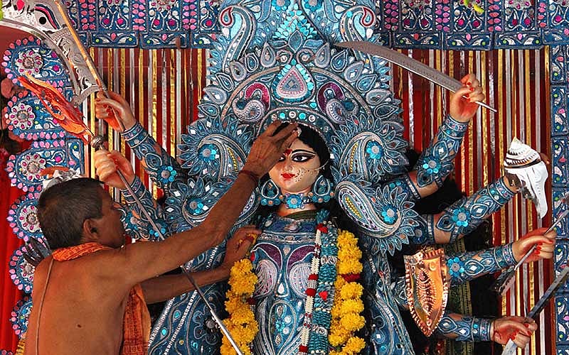 A Hindu priest worships an idol of the Hindu goddess Durga at a pandal or temporary platform during the Durga Puja festival