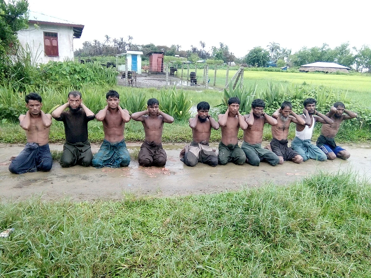 This photo was taken on the day the 10 Rohingya men were killed. Paramilitary police officer Aung Min, left, stands guard behind them. The picture was obtained from a Buddhist village elder, and authenticated by witnesses