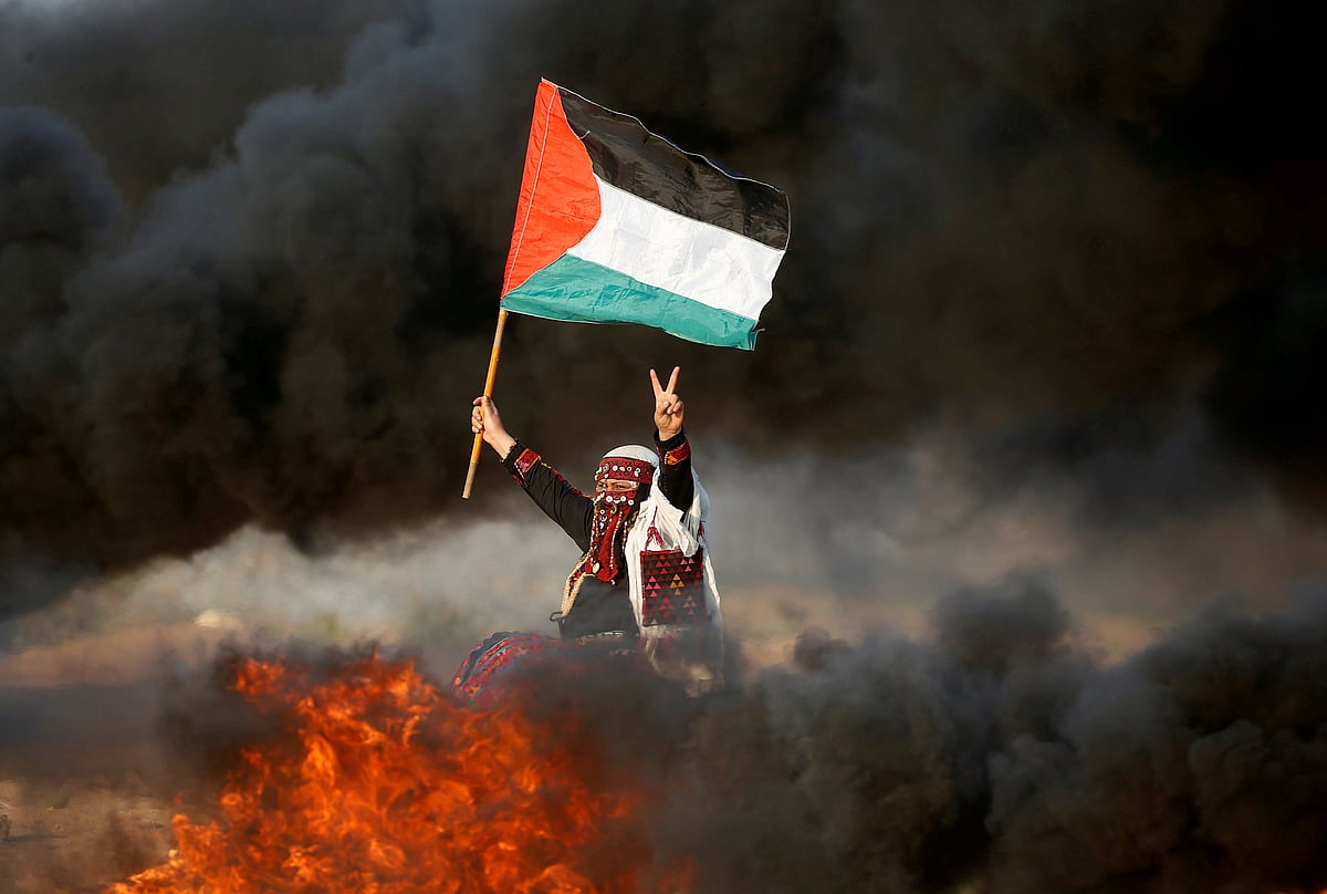 A woman waves a Palestinian flag during a protest calling for lifting the Israeli blockade on Gaza and demanding the right to return to their homeland, at the Israel-Gaza border fence east of Gaza City on 28 September. Photo: Reuters
