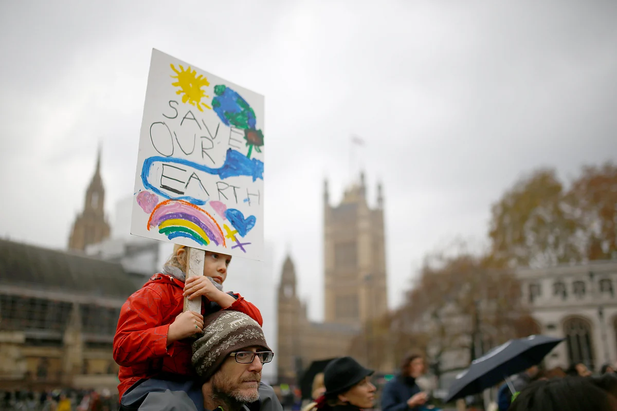 A demonstrator carries a child on his shoulders during a protest about the environment in Parliament Square, central London, Britain.