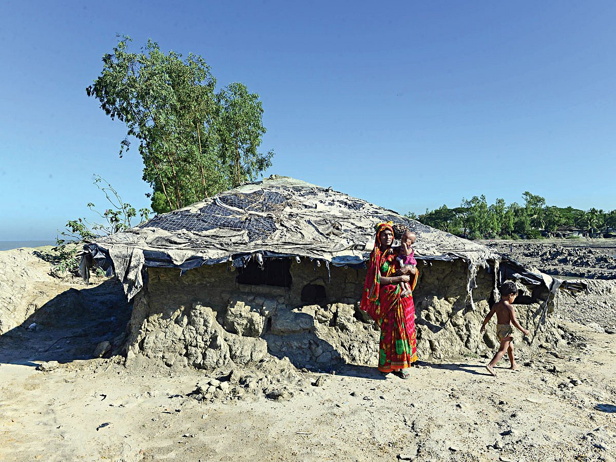 কুতুবদিয়া দ্বীপে নিজ ঘরের পাশে সন্তানসহ দাঁড়িয়ে আছেন হামিদা বেগম। জোয়ারের সময় এ ঘর ডুবে গেলে অন্যত্র চলে যেতে হয় হামিদাকে। দ্বীপ উপজেলাটিতে এখনো প্রায় এক লাখ লোক বাস করে। বাংলাদেশের একটি বেসরকারি সংস্থা সতর্ক করে দিয়ে বলেছে, আগামী ৫০ বছরের মধ্যে পুরো দ্বীপটিই পানির নিচে তলিয়ে যাবে। ছবিটি গত বছরের ২০ নভেম্বর তোলা