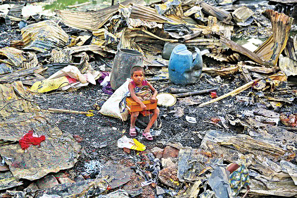 পুড়ে যাওয়া বসতঘরের জায়গায় খোলা আকাশের নিচে বসে আছে শিশু আজিজুর রহমান। কড়াইল বস্তি থেকে তোলা।